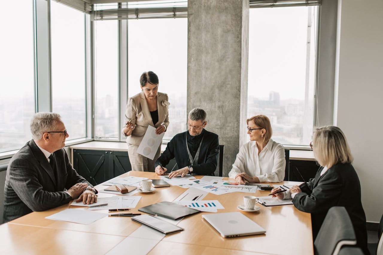Professionals discussing documents during a business meeting in a modern office setting.